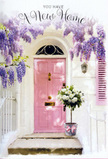 The photograph captures a tender housewarming moment at a quiet East Ham entrance, where architecture and floristry blend into a single, welcoming gesture. A pale pink door stands at the centre, its gentle colour softly luminous against crisp whitewashed walls that frame it like a simple canvas. Above, generous cascades of lavender wisteria pour down from an unseen vine, each trailing cluster dense with small blossoms that seem to hum with early-spring energy. The flowers arc over a delicately painted shutter, creating a natural archway that pulls your attention toward the doorway and the story beginning there. On the stone step below, a rounded metal bucket in a cool, dove-grey hue holds an abundance of white and cream roses, their petals plush, layered, and delicately shadowed. Wisps of fresh green foliage are threaded among the blooms, providing a soft, natural contrast that hints at gardens and tree-lined streets around East Ham. A narrow pink ribbon encircles the bucket, tied neatly so that its satin ends echo the colour of the door and complete the pastel harmony of the scene. The light feels like a still afternoon near Central Park or along the quieter side roads off Barking Road, bright but gentle, casting only the faintest of shadows. Altogether, the arrangement seems like a heartfelt delivery left on the step-a florist's way of saying congratulations on your new place, may this threshold see laughter, friendship, and countless beautiful everyday moments as life in East Ham unfolds just beyond that softly painted door.